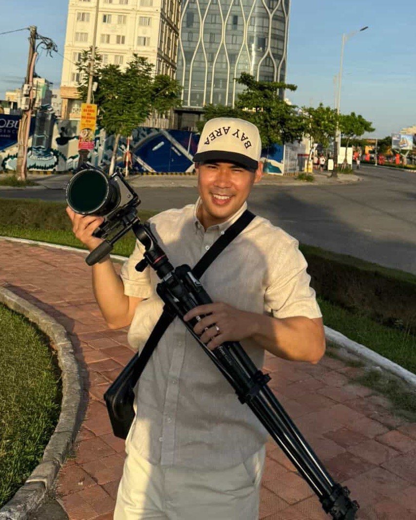 Vang Ha smiling with his camera and tripod
