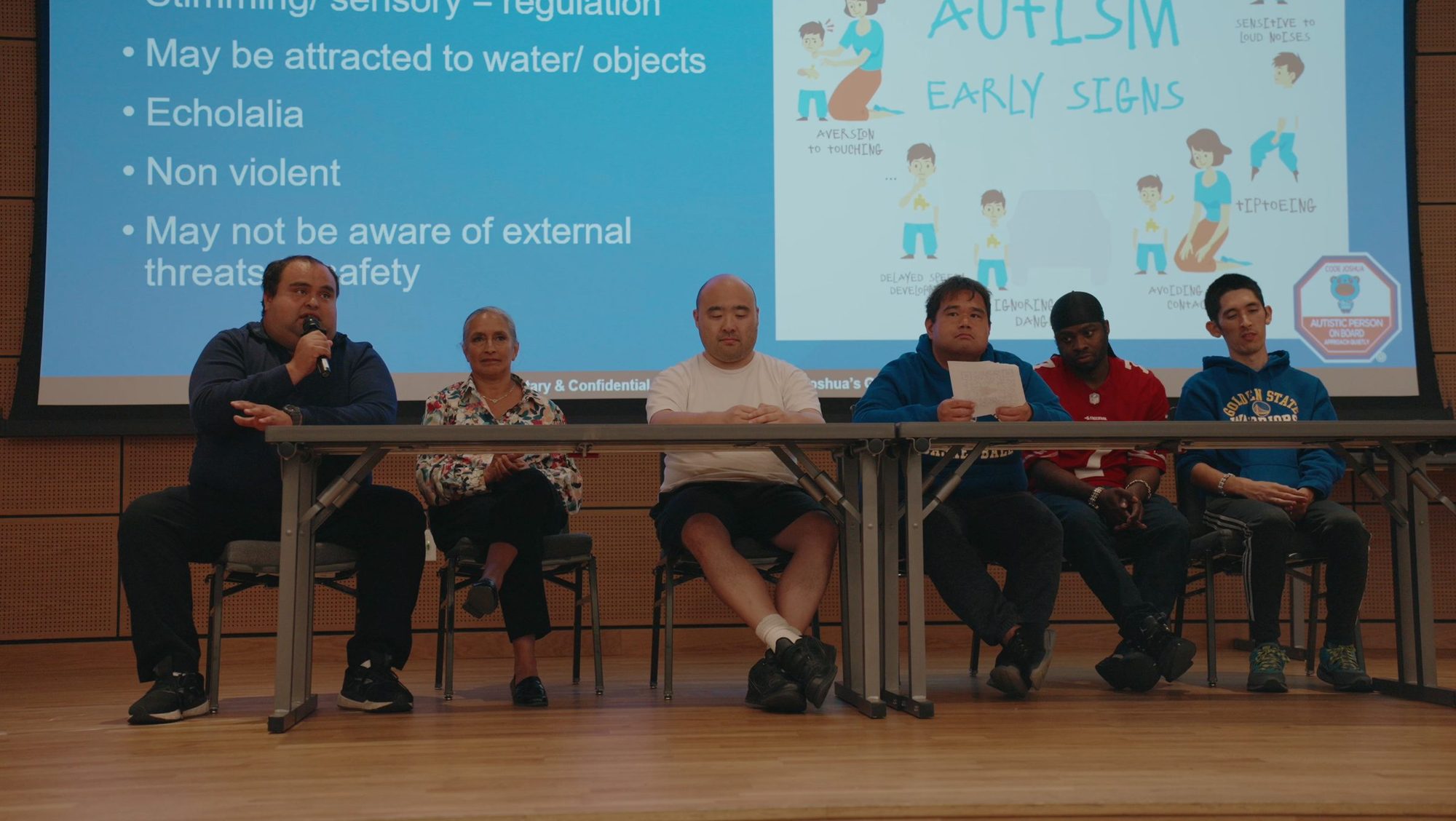 Panel seated in front of a presentation on early signs of autism