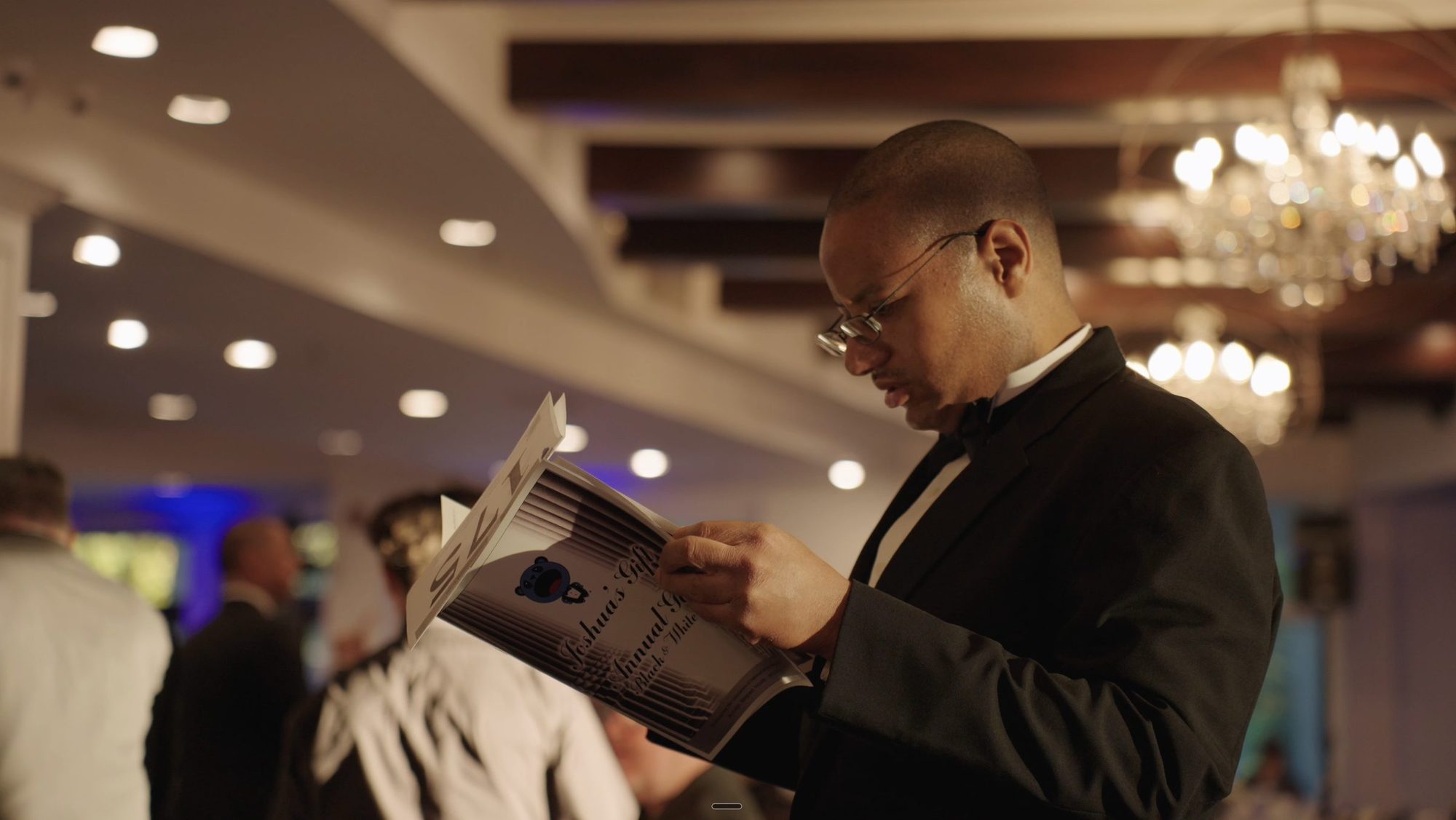 Guest in a tuxedo reading the gala program
