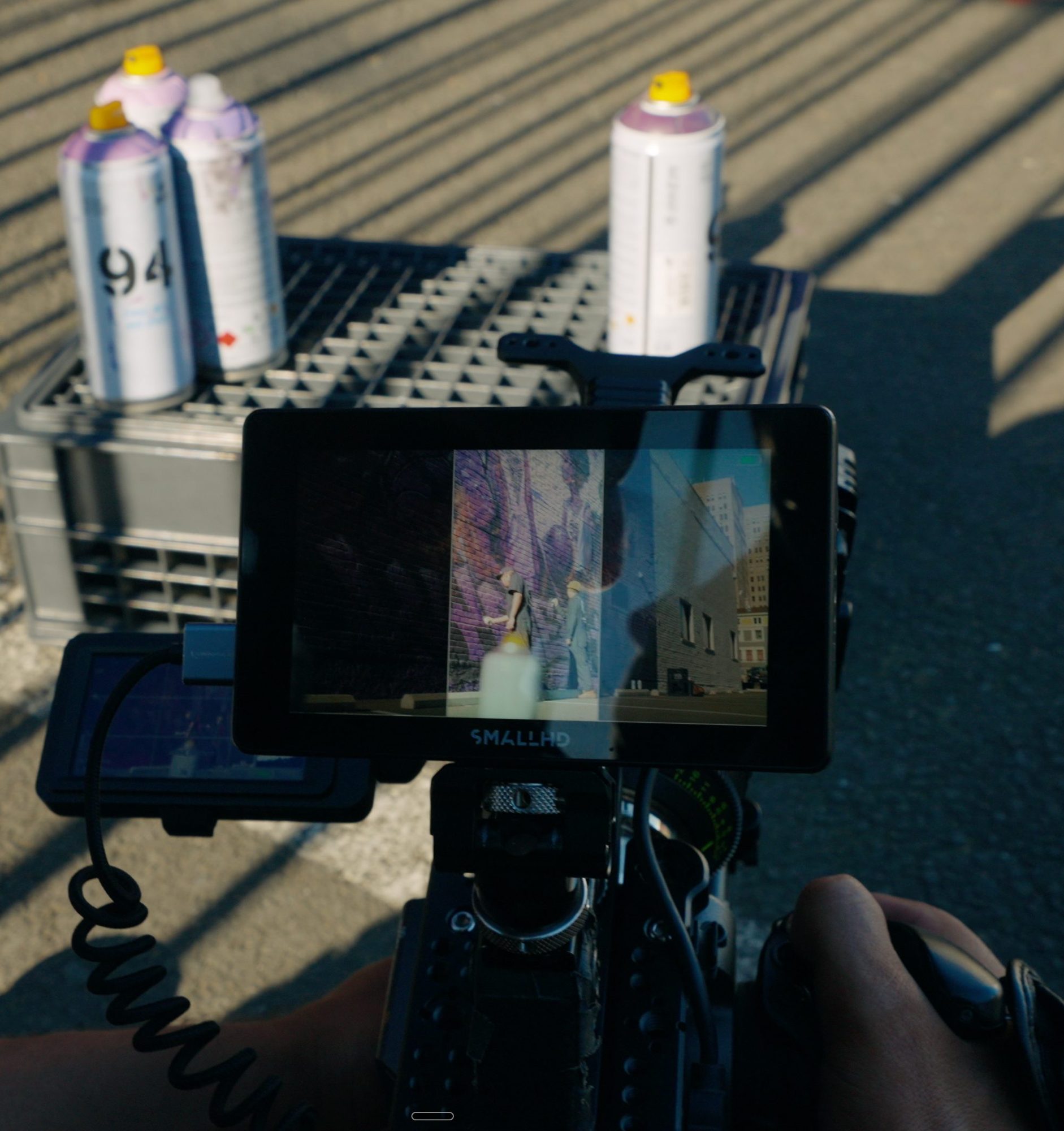 Camera monitor framing the shot beside cans of spray paint
